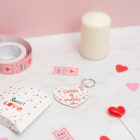 Llavero de enamorados con forma de corazón. Personalizado con nombres y fecha. Fondo con diseño con temática de enamorados de fondo